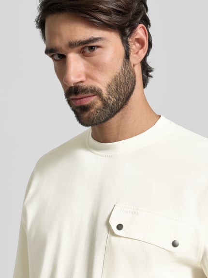 Männermodel trägt Relaxed Fit Langarmshirt aus Baumwoll-Mix von Barbour in Unifarbe mit Brusttasche und Rundhalsausschnitt, Nahaufnahme Oberkörper.