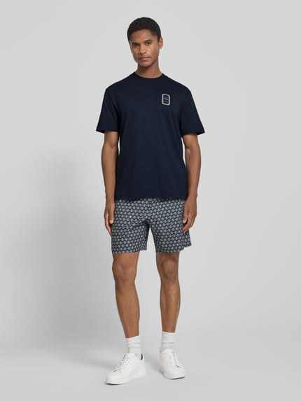 Männermodel trägt dunkelblaues Regular Fit T-Shirt aus reiner Baumwolle Modell 'CN Tenniscourt Backprint' von Lacoste, Herren T-Shirt, Ganzkörperansicht von vorne.