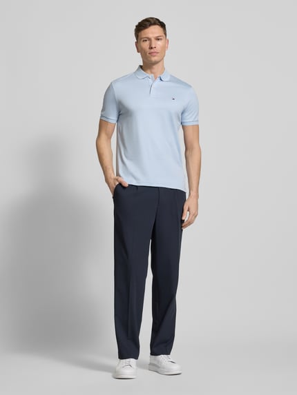 Mannenmodel draagt lichtblauw Regular fit Poloshirt uit puur katoen Model 'LIQUID COTTON' van Tommy Hilfiger in mêlee-look met gestikt logo, polokraag, korte mouw met geribde mouwboord en rompzoom met zijsplitten, pure katoen, volledig lichaam van voren.