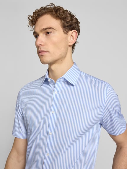 Männermodel trägt Slim Fit Business-Hemd aus Baumwolle mit Kentkragen von Jake*s, blauer Streifen, Knopfleiste, Nahaufnahme Oberkörper.