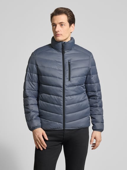Männermodel trägt Regular Fit Steppjacke mit vertikaler Reißverschlussbrusttasche von Tom Tailor Denim, Optik: Unifarben, Stehkragen, Reißverschluss, Langarm, paspelierter Rumpfabschluss, seitliche Eingrifftaschen, glatte Struktur, Ganzkörperansicht von vorne.