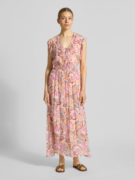 Kobiece model prezentuje długą sukienkę Maxikleid mit V-Ausschnitt und Schnürung Modell 'CALI' od SUNCOO PARIS, linia a, wzór na całej powierzchni, dekolt w serek, wiązanie, długość tyłu w rozmiarze S: 133 cm, szerokość w rozmiarze S: 33 cm, pastelowe kolory, lekka tekstura, Ganzkörperansicht von vorne.