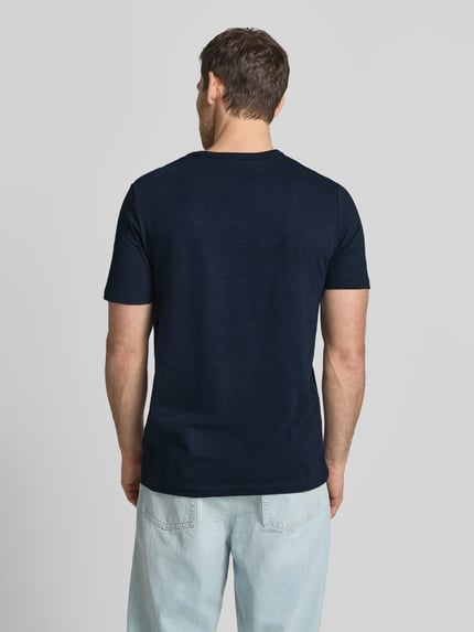 Męski model nosi Regular Fit T-Shirt aus reiner Baumwolle od s.Oliver RED LABEL, efekt: jednolity kolor, krój regular fit, nadruk z motywem, rękaw: krótki rękaw, bawełna, Ganzkörperansicht Rückansicht.