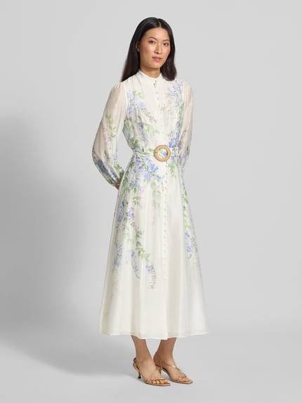 Frauenmodel trägt Abendkleid aus Lyocell-Leinen-Mix Modell 'Sheridan' von Forever New, florales Muster, tailliert, Stehkragen, 3/4-Arm, Knopfleiste, Taillengürtel, blickdichter Unterrock, helle Pastellfarben, Ganzkörperansicht von vorne.