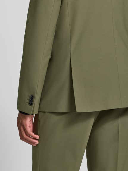 Männermodel trägt Super Slim Fit Sakko aus Woll-Mix Modell 'Arti 253X' von HUGO in Olivgrün, glatte Textur, Ganzkörperansicht Rückansicht.