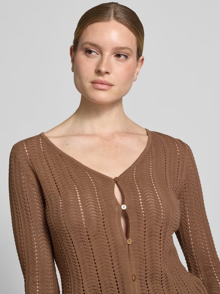 Frauenmodel trägt Cardigan mit V-Ausschnitt und Knopfleiste von Rich & Royal aus Reine Baumwolle, Ajour, Straight, Trompetenärmel, Nahaufnahme Oberkörper.