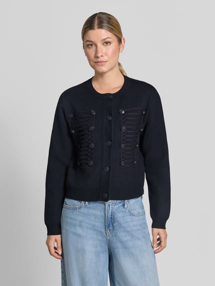 Frauenmodel trägt Cardigan aus Viskose-Mix mit Zierknöpfen Modell 'GENIO' von MANGO, regular Fit, Rundhalsausschnitt, Ganzkörperansicht von vorne.