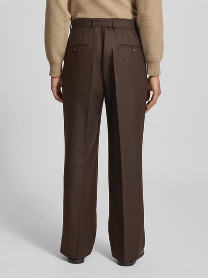 Männermodel trägt Regular Fit Bundfaltenhose aus Schurwolle von Officine Générale, braun unifarben, Twill mit Struktur, Rückansicht Ganzkörperansicht.