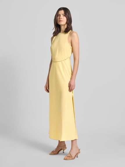 Vrouwenmodel draagt Maxikleid met Ketten-Detail van ARMANI EXCHANGE, satijn, getailleerd model, ronde hals, geel, geheel van voren.