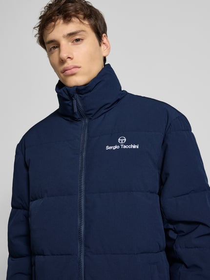 Mannelijk model draagt donkerblauwe Steppjacke mit Stehkragen Modell 'NILO' van SERGIO TACCHINI, detailopname bovenlichaam, regular fit, materiaal-mix met stretch, label-stitching op borst, rits en steekzakken.