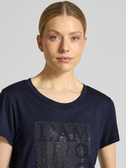 Vrouwenmodel draagt T-shirt met Ziersteinbesatz und Rundhalsausschnitt van monari in donkerblauw, mix van katoen en micromodal, regular fit, ruglengte bij maat 36: 58 cm, Nahaufnahme bovenlichaam.