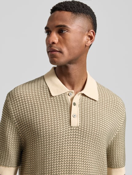 Męski model nosi Regular Fit Poloshirt in Strick-Optik Modell 'Kingsley' von Jack & Jones Premium z bawełny, krój regular fit, imitacja dzianiny, z krótkim rękawem, kołnierzyk polo, elastyczne wykończenia, długość tyłu w rozmiarze M: 77 cm, zbliżenie na górną część ciała