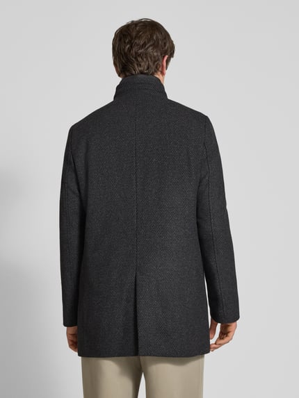 Männermodel trägt Mantel mit Stehkragen Modell 'Outdoor-Mantel' von S. OLIVER BLACK LABEL in dunklem Melange mit Strukturmuster, Ganzkörperansicht Rückansicht