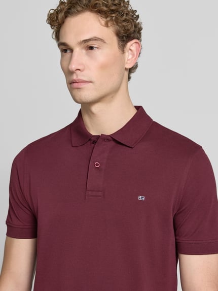 Männermodel trägt Regular Fit Poloshirt mit Stitching von Christian Berg Men in Dunkelrot, Reine Baumwolle, mit Knopfleiste, Nahaufnahme Oberkörper. Rückenlänge bei Größe M: 64 cm.