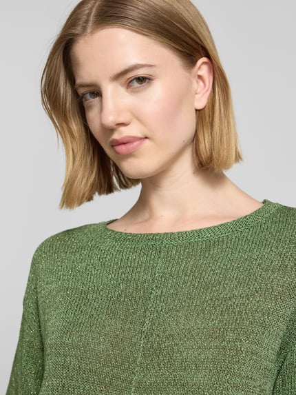 Frauenmodel trägt Relaxed Fit Pullover mit U-Boot-Ausschnitt von s.Oliver BLACK LABEL, schimmernde Optik, Strick, Label-Patch, Nahaufnahme Oberkörper.