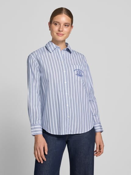 Vrouwenmodel draagt Relaxed Fit Langarmbluse aus reiner Baumwolle van GANT in lichtblauw met witte strepen, Dames blouse met lange mouwen, puur katoen, voorkant volledig zichtbaar, Ganzkörperansicht van voren.