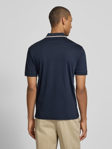 Männermodel trägt Slim Fit Poloshirt aus reine katoen Modell 'PENROSE' van BOSS, uni donkerblauw, korte mouw, achterkant, ganzkörperansicht rückansicht.
