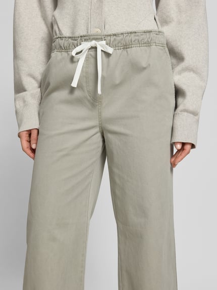 Frauenmodel trägt Wide Fit Jeans mit Tunnelzug von Juvia in Hellgrau, reine Baumwolle, Eingrifftaschen, Nahaufnahme Oberkörper.