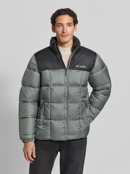 Männermodel trägt Regular Fit Jacke in Stepp-Optik Modell 'Puffect™' von Columbia, dezente Grau- und Schwarztöne, Logo-Print, Ganzkörperansicht von vorne. Schulterbreite, Rückenlänge, Brustweite und Ärmellänge laut Größenangabe M.