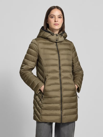 Frauenmodel trägt Steppjacke mit Zweiwege-Reißverschluss von FUCHS SCHMITT in Oliv mit Kapuze, Reißverschlusstaschen, Ganzkörperansicht von vorne. Rückenlänge 83 cm, Schulterbreite 42 cm, Brustweite 51 cm, Ärmellänge 64 cm, Slim Fit.