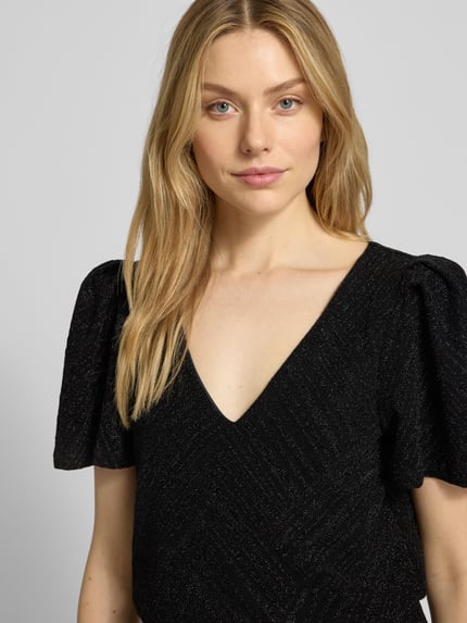 Frauenmodel trägt Jumpsuit mit V-Ausschnitt Modell 'zoe' von Vila in Schwarz, lockerer Schnitt, feine Struktur, Nahaufnahme Oberkörper.