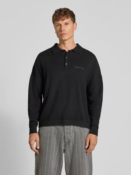 Mannenmodel draagt zwarte gebreide pullover met polokraag en knoopsluiting van RETERNITY, Materiaalmix met katoen, regular fit, labelstitching, ruglengte maat M 65 cm, mouwlengte maat M 48 cm, rechte lijnen en zachte textuur, vooraanzicht bovenlichaam.