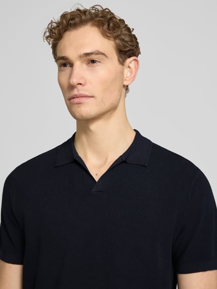 Męskimodel nosi Regular Fit Poloshirt aus Lyocell-Mix mit Seiden-Anteil von Profuomo, czarny, fakturowany wzór, dekolt w serek, Nahaufnahme górnej części ciała. Długość tyłu w rozmiarze M: 67 cm.