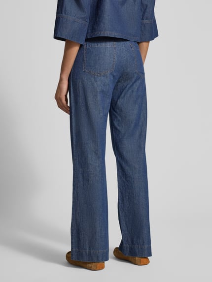 Frauenmodel trägt Flared Hose mit aufgesetzten Taschen von Jake*s Collection, granatowy denim, rozkloszowany krój, nakładane kieszenie z tyłu, zapięcie na guzik i zamek błyskawiczny, szerokość w rozmiarze 38: 40 cm, długość wewnętrzna nogawki w rozmiarze 38: 79 cm, całkowita sylwetka z tyłu