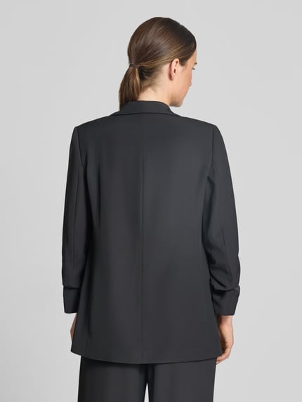 Frauenmodel trägt Relaxed Fit Blazer mit Pattentaschen von Jake*s Collection in Schwarz, glatte Struktur, Material-Mix mit Stretch, Ganzkörperansicht Rückansicht.