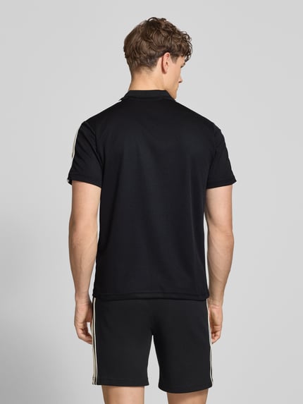 Männermodel trägt Regular Fit Poloshirt mit Logo-Stitching Modell 'EGEO' von SERGIO TACCHINI in Schwarz, Kurzarm, Rückenansicht, Ganzkörperansicht Rückansicht.