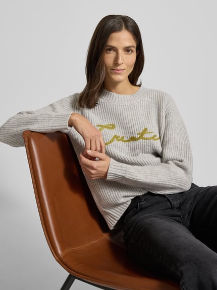 Kobiece model prezentuje Sweter z dzianiny z okrągłym dekoltem model 'Brynna' od MOS MOSH, kolor szary, bawełna, krój relaxed fit, haft, półzbliżenie na górną część ciała.