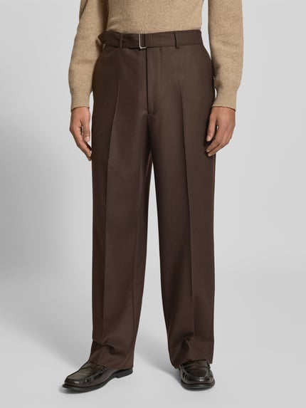 Männermodel trägt Regular Fit Bundfaltenhose aus Schurwolle von Officine Générale in Dunkelbraun, Struktur mit Gürtelschlaufen, Nahaufnahme Unterkörper