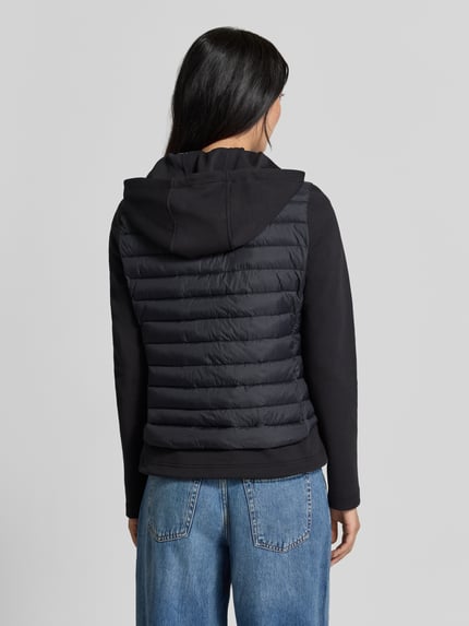 Modelka prezentuje kurtkę 'Jacke aus Baumwoll-Mix in Stepp-Optik' od FUCHS SCHMITT, czarny kolor, z efektem pikowania, kaptur z tunelem, krój taliowany, mieszanka bawełny, zamek błyskawiczny dwustronny, długość tyłu w rozmiarze 36: 59 cm, szerokość ramion w rozmiarze 36: 40 cm, szerokość w klatce piersiowej w rozmiarze 36: 48 cm, długość rękawa w rozmiarze 36: 67 cm, widok całej sylwetki z tyłu.
