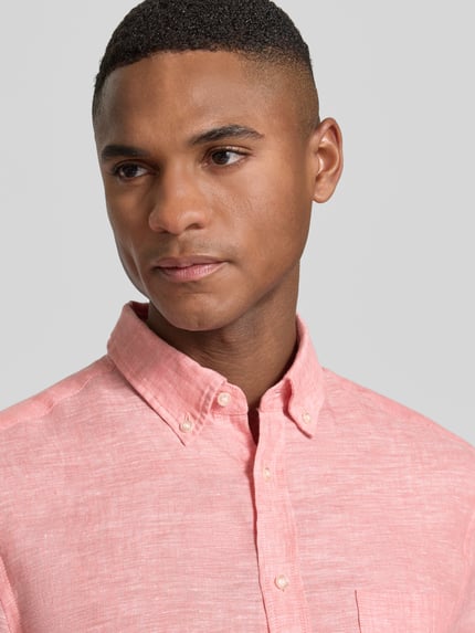 Mężczyznamodel nosi Slim Fit Leinenhemd mit Brusttasche von Christian Berg Men, różowy len, kołnierzyk typu button down, listwa guzikowa, brustasza, krój slim fit, zbliżenie na górną część ciała