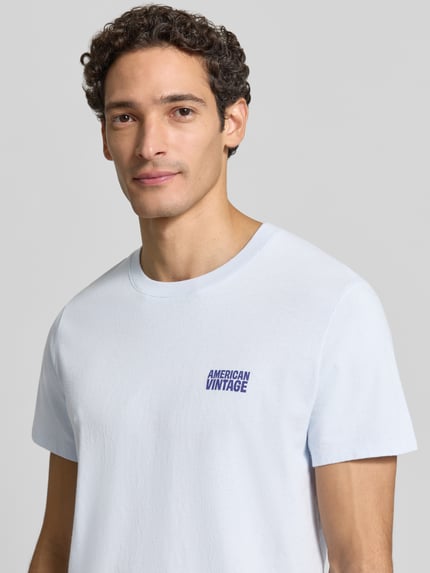 Männermodel trägt T-Shirt mit Logo und Rundhalsausschnitt Modell 'YKOBOW' von American Vintage aus reiner Baumwolle, Nahaufnahme Oberkörper, Regular Fit, Rückenlänge bei Größe M: 70 cm.