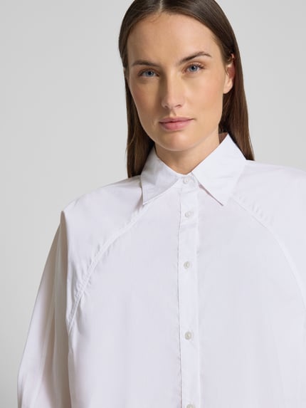Frauenmodel trägt Oversized Hemdbluse aus reiner Baumwolle Modell 'BELENTA' von BOSS Orange, unifarben, Nahaufnahme Oberkörper.