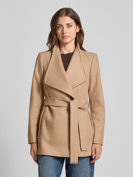Vrouwenmodel draagt Kurzmantel aus Woll-Mix mit Bindegürtel Modell 'ROSESS' van Ted Baker, beige, regular fit, gladde textuur, staande kraag, labeldetail, bindriem, Ganzkörperaanzicht van voren.