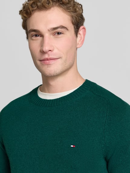 Männermodel trägt Regular Fit Pullover aus Lammwoll-Mix von Tommy Hilfiger, jednokolorowy, imitacja dzianiny, matowy, struktura, detal z logo, drobny splot, okrągły dekolt, długi rękaw, prążkowane wykończenia, wykończenie: prążkowane, drobny splot, Ganzkörperansicht von vorne
