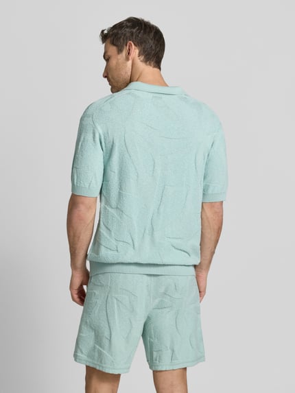 Männermodel trägt Relaxed Fit Poloshirt aus reiner Baumwolle Modell 'ASURFO' von BOSS Orange, Optik: Unifarben, Struktur, Ganzkörperansicht Rückansicht.