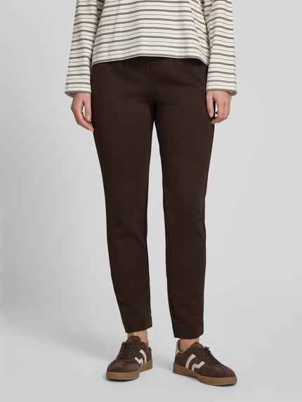 Frauenmodel trägt Loose Fit Bundfaltenhose aus Viskose-Mix von Tom Tailor in Dunkelbraun, glatte Oberfläche, Ganzkörperansicht von vorne, Damen Bundfaltenhose von Tom Tailor.