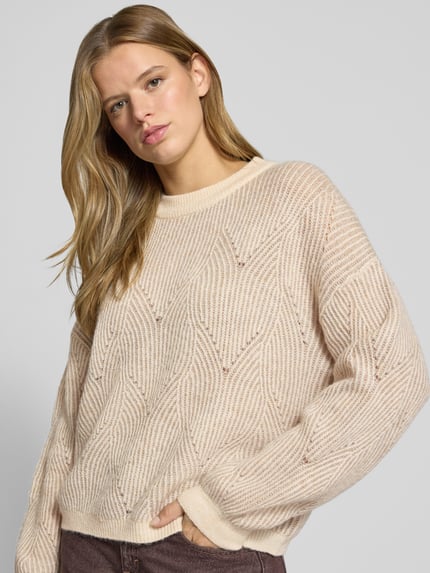 Frauenmodel trägt Pullover mit plastischer Strickstruktur von PIECES, geometrisches Allover-Muster in Strickoptik, Nahaufnahme Oberkörper.