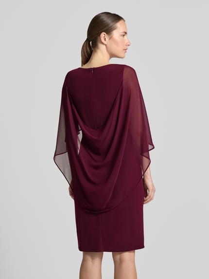 Frauenmodel trägt Tailliertes Cocktailkleid mit Strasssteinbesatz von Vera Mont in Dunkelrot, feine Transparenz, glatte Struktur, Ganzkörperansicht Rückansicht, Damen Cocktailkleid von Vera Mont.