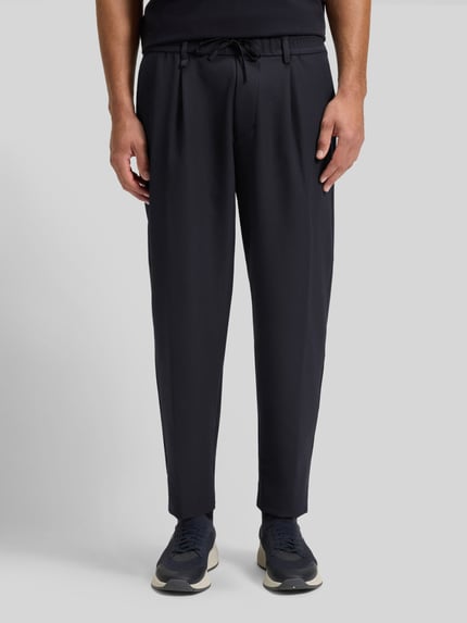 Männermodel trägt Tapered Bundfaltenhose mit halbelastischer Bund Modell 'CONVERT-PLEAT' von BOSS Green, unifarben, Nahaufnahme Unterkörper