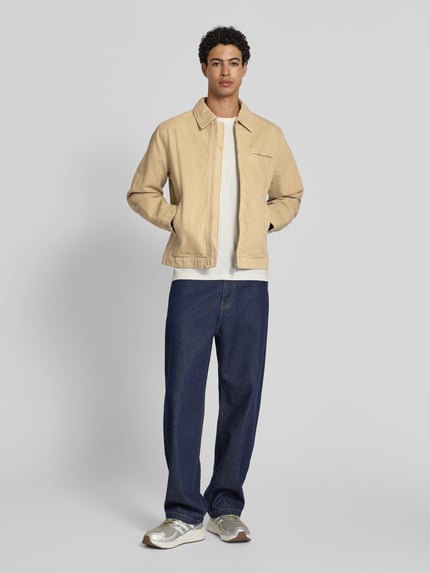 Männermodel trägt Jacke mit Zweiwege-Reißverschluss von Jack & Jones in Beige aus Reine Baumwolle, Regular-Fit, Umlegekragen, Ganzkörperansicht von vorne.