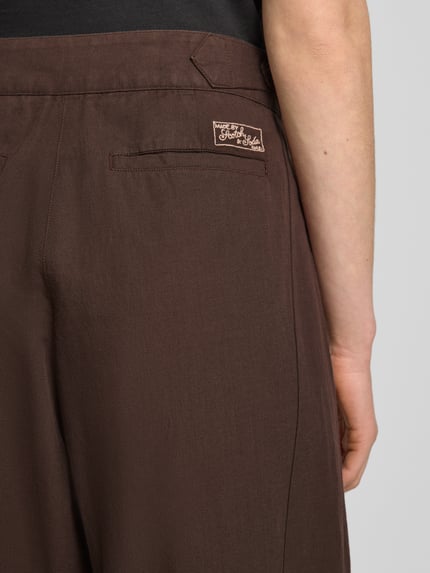 Frauenmodel trägt Wide Leg Hose mit Eingrifftaschen Modell 'QUINN' von Scotch & Soda in Braun, Baumwoll-Leinen-Mix, Detailaufnahme Rückansicht.