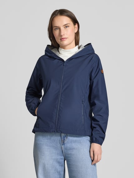 Frauenmodel trägt dunkelblaue Regular Fit Jacke mit Zweiwegereißverschluss Modell 'Stella' von SAVE THE DUCK, Eingrifftaschen, Ganzkörperansicht von vorne. Rückenlänge 60 cm, Schulterbreite 42 cm, Brustweite 52 cm, Ärmellänge 64 cm.