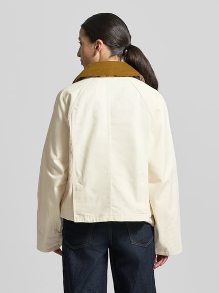 Frauenmodel trägt Regular Fit Parka aus reiner Baumwolle von Barbour in Unifarbe mit Umlegekragen und langen Ärmeln, Ganzkörperansicht Rückansicht.