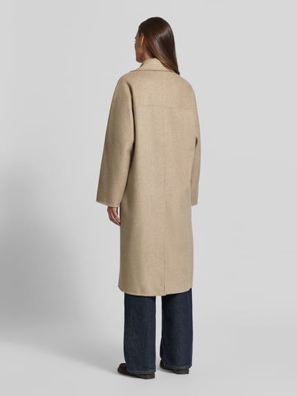 Frauenmodel trägt Regular Fit Mantel aus elastischem Baumwoll-Mix Modell 'PICAROL' von MANGO in Beige, glatte Textur, Ganzkörperansicht Rückansicht. Rückenlänge 112 cm, Schulterbreite 42 cm, Brustweite 56 cm, Ärmellänge 58 cm.