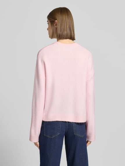 Vrouwenmodel draagt Relaxed Fit Strickpullover met crew neck model 'SIMONI' van Only in melange roze, geribde randen, gebreid materiaal. Volledige lichaamsopname van achteren.