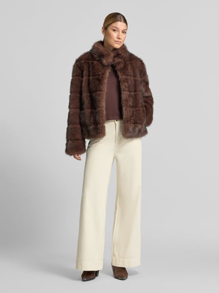 Frauenmodel trägt Jacke aus Kunstfell mit Steppnähten von PETITE M., braune, weiche Textur, Regular Fit, Ganzkörperansicht von vorne.